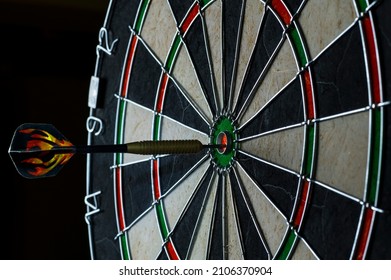 Side View Of Professional Darts Board With Arrow In Bull's Eye In The Dark. 