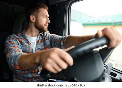 Side view of professional driver behind the wheel in truck's cabin