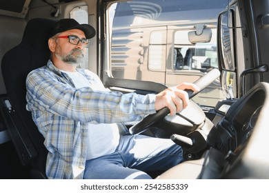 Side view of professional driver behind the wheel in truck's cabin.