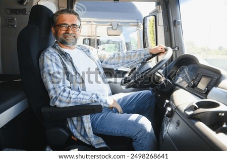 Side view of professional driver behind the wheel in truck's cabin.