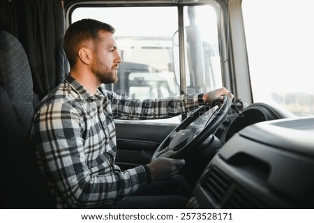 Side view of professional driver behind the wheel in truck's cabin.