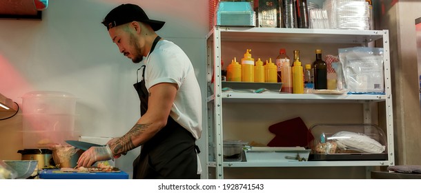 Side view of professional experienced sushi chef cutting ingredients with a knife for spreading them over nori sheet while making delicious rolls at commercial kitchen. Asian cuisine concept - Powered by Shutterstock