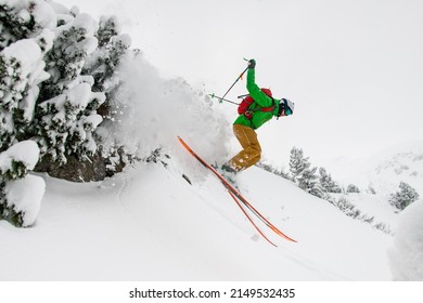 Side view of professional male skier energy sliding down the snow-covered mountain slope. Freeride skiing concept