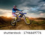 Side View of the Professional Motorcycle Rider Driving on the mountains and Further Down the Off-Road Track. It
