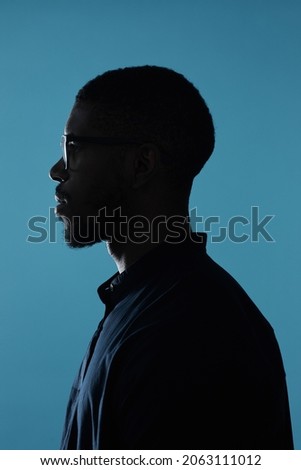 Side view profile outline of African-American male silhouette against deep blue background