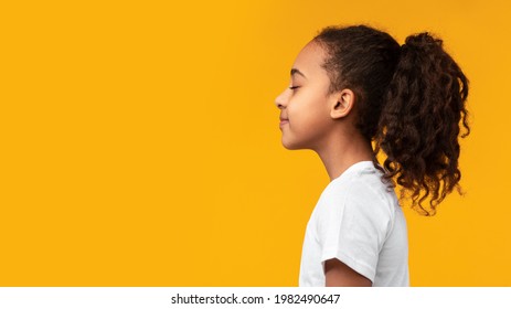 Side View Profile Portrait Of African American Girl In White T-shirt Posing With Closed Eyes And Curly Ponytail Hair Isolated On Yellow Studio Background Wall. Empty Free Copy Space, Banner, Panorama