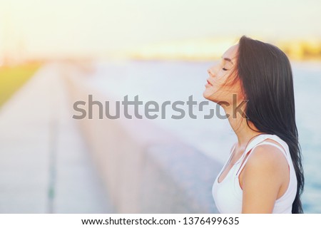 Side view profile portrait of a happy brunette woman relaxing breathing fresh air outdoors in summer Girl closed eyes doing deep breath exercises. Positive emotion success, peace of mind, zen concept.