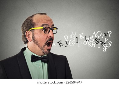 Side view profile portrait middle aged business man talking symbols alphabet letters coming out of his mouth isolated grey wall background. Human face expression. Communication intelligence concept 