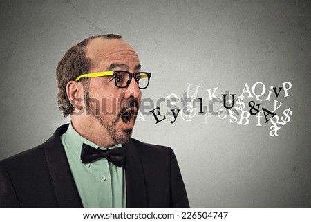 Side view profile portrait middle aged business man talking symbols alphabet letters coming out of his mouth isolated grey wall background. Human face expression. Communication intelligence concept 
