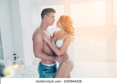Side view profile of stunning, young macho with naked  in jeans embracing with sexy woman with perfect buttoks, butt, curly hair, in white bikini, looking to each other, celebrate valentine day