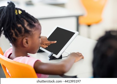 Side view of pupil using tablet pc in classroom at elementary school