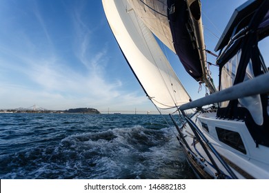 Side View Of Racing Sailboat As It Heads For The Bay Bridge In San Francisco Bay On A Sunny Day