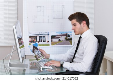 Side View Of Real Estate Agent Working On Computer In Office