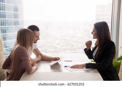 Side view of realtor and young couple sitting at office desk discussing property for sale. Potential buyers holding house plan, considering investment in home or taking loan to purchase real estate  - Powered by Shutterstock