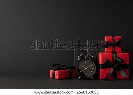Side view of red and black gift boxes with black ribbon decoration and an alarm clock on a dark background suggesting a Black Friday sale celebration