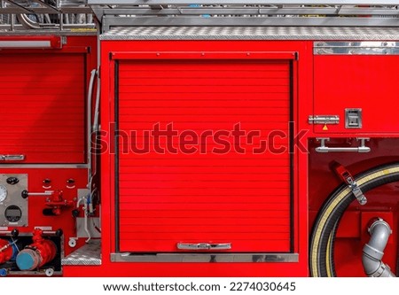 Side view of a red fire engine with a closed roller door for copy space. Background motif for flyers on the subject of fire brigades.