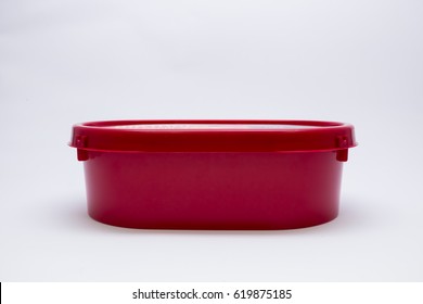 side view of red oval ice cream plastic tub and lid with blank red label for text isolated on white background