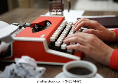 Side view of red typewriter, cup of coffe, crumpled paper
