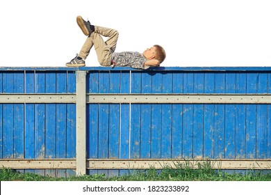 Side View Of Relaxed Boy In Casual Clothes Lying On Blue Hockey Rink Fence And Dreaming Against White Background