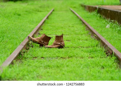 Side view, Retro brown boot are placed on the tracks. In the rainy season the old railway tracks are covered with green grass.