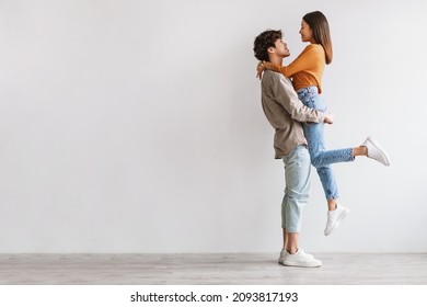Side view of romantic young Asian guy holding and hugging his beloved girlfriend against white studio wall, copy space. Full length fo millennial spouses expressing love and affection - Shutterstock ID 2093817193