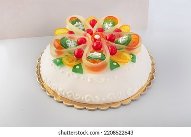Side view of round white wedding cake decorated with frosted icing and brightly coloured candied fruits - Shutterstock ID 2208522643