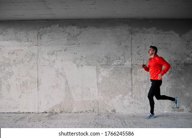 Side view of runner running fast under the bridge.