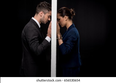 Side View Of Sad Couple In Formal Wear Separated By Wall Isolated On Black