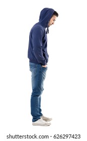 Side View Of Sad Upset Man In Hooded Shirt With Hands In Pockets Looking Down. Full Body Length Portrait Isolated Over White Studio Background. 