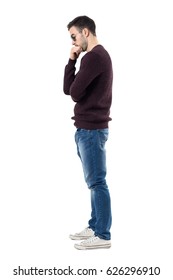 Side View Of Sad Worried Man In Maroon Pullover Looking Down. Full Body Length Portrait Isolated Over White Studio Background. 