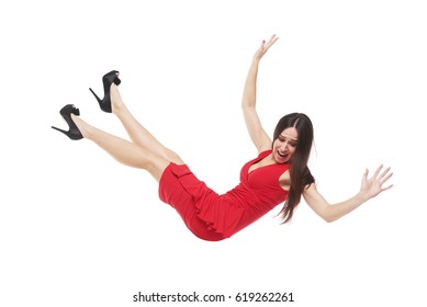 Side view of a scared female in red dress falling down. Young long-haired woman looking down while floating in the air 