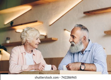 side view of senior couple having conversation while drinking coffee together in cafe