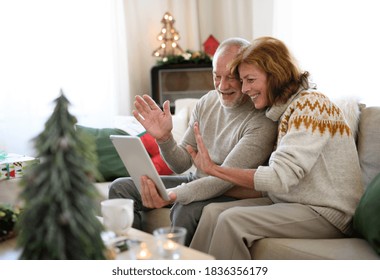 Side view of senior couple indoors at home at Christmas, having video call with family. - Powered by Shutterstock