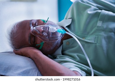 Side view of senior ill patient breathing on oxygen ventilator mask due to coronavirus or covid-19 breathlessness viral infection at hospital.