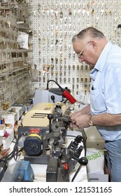 Side View Of Senior Locksmith Making Key In Store