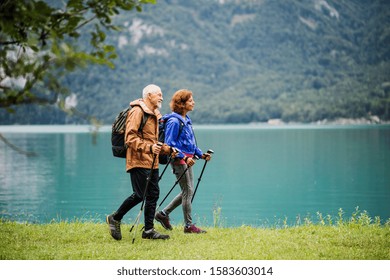 A Side View Of Senior Pensioner Couple Hiking By Lake In Nature.