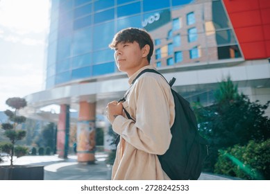 side view A serene portrait captures a young Asian student, his backpack a constant companion, as he delves into the world of academia amidst the tranquil beauty of the college campus.
