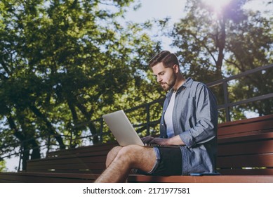 Side view serious freelancer programmer young man 20s wearing blue shirt shorts sit on bench work online laptop pc computer rest relax in spring green city park outdoor on nature Urban leisure concept - Powered by Shutterstock