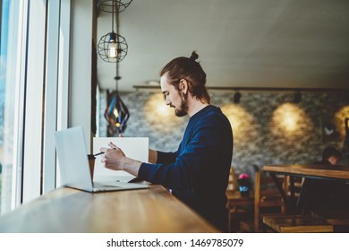 Side View Of Serious Skilled Male Student Studying Information For Knowledge Textbook For Put Into Chapter Of Course Work, Millennial Man Analyzing Data From Laptop Comture And Paper Notepad