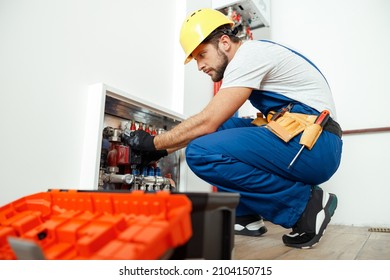 Side View Of Serious Technician, Plumber In Uniform Using Tools From Toolbox While Checking Water Pipes In Apartment