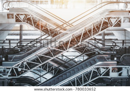 Side view of several criss-cross positioned empty modern escalators with opened internal mechanisms and gears in interior of contemporary airport terminal, railway station or shopping mall on daytime