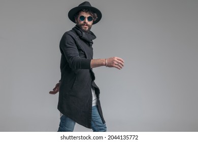 Side View Of A Sexy Casual Man Walking One Way And Looking The Other On Gray Background