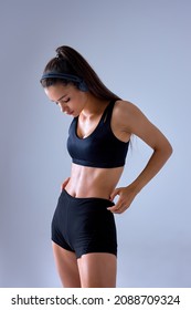 side view of sexy woman showing perfect body and sports stomach. Healthy fitness and eating lifestyle concept. Fitness sporty woman showing well trained body,straighten shorts isolated on gray