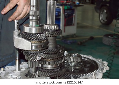 Side view of shafts and gears of a partially disassembled mechanical transmission in an auto repair shop - Shutterstock ID 2122160147