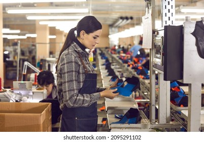 Side View Of Shoe Factory Worker Standing In Big Sewing Workshop And Checking Quality Of Unfinished Details Of Future Sneakers. Mass Footwear Manufacturing Concept