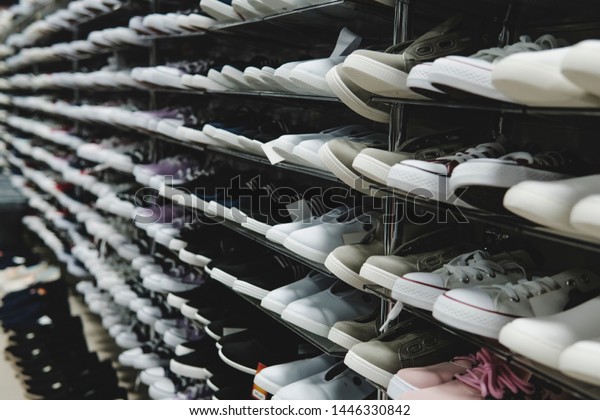 Side view of shoe store shelves with of lots of
sneakers on sale. Low-budget comfortable footwear shopping. Unisex
stylish teenager shoes. Rows of new runners in shoe shop. Stands of
cheap trainers.
