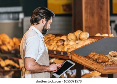 side view of shop assistant in apron using tablet with blank screen in supermarket - Powered by Shutterstock