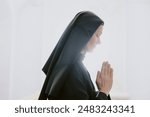 Side view shot of faithful mature Caucasian Catholic nun praying to God, white background, copy space