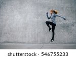 Side view shot of fit young woman doing cardio interval training against grey background. Fitness female exercising outdoors in morning.