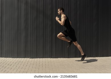 A side view shot of a fit young, athletic man jumping and running. doing cardio interval training against a grey background. Fitness male exercising, outdoors in the morning. - Shutterstock ID 2135683681
